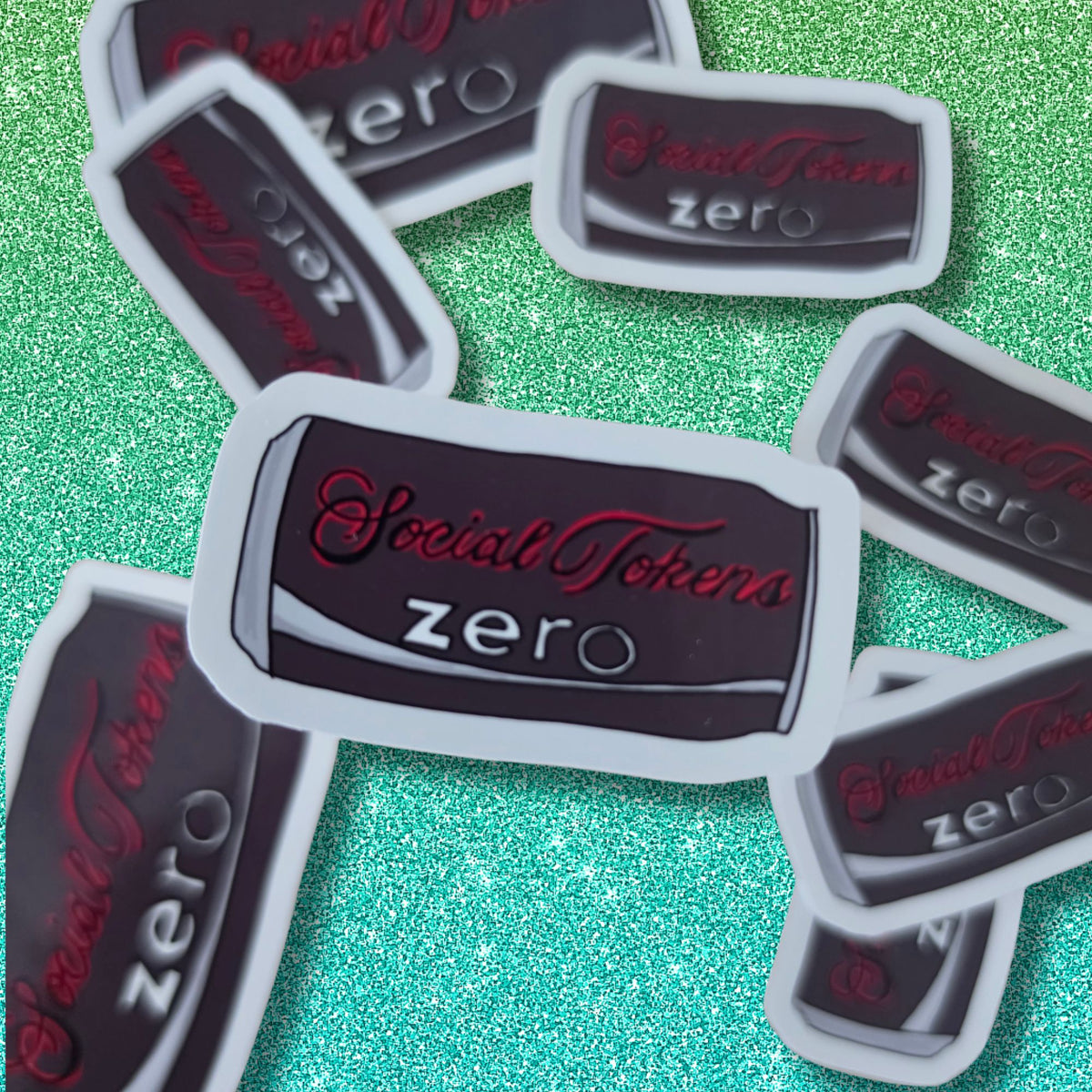 Several die-cut stickers featuring the text 'SocialTokens zero' in red and gray on a drinks can, arranged on a sparkling mint green surface.