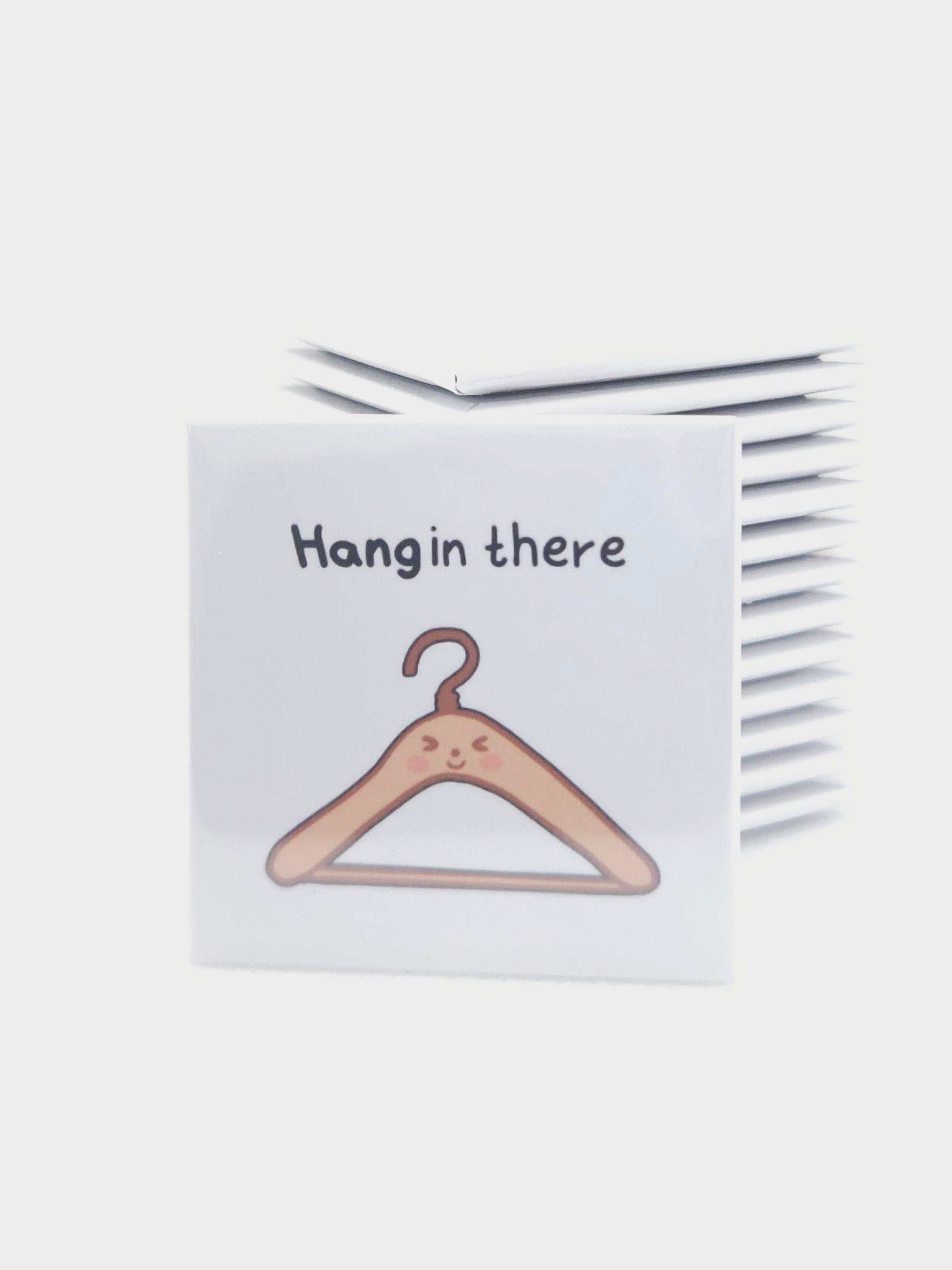 magnet with a hanger illustration and 'Hang in there' text on a white background