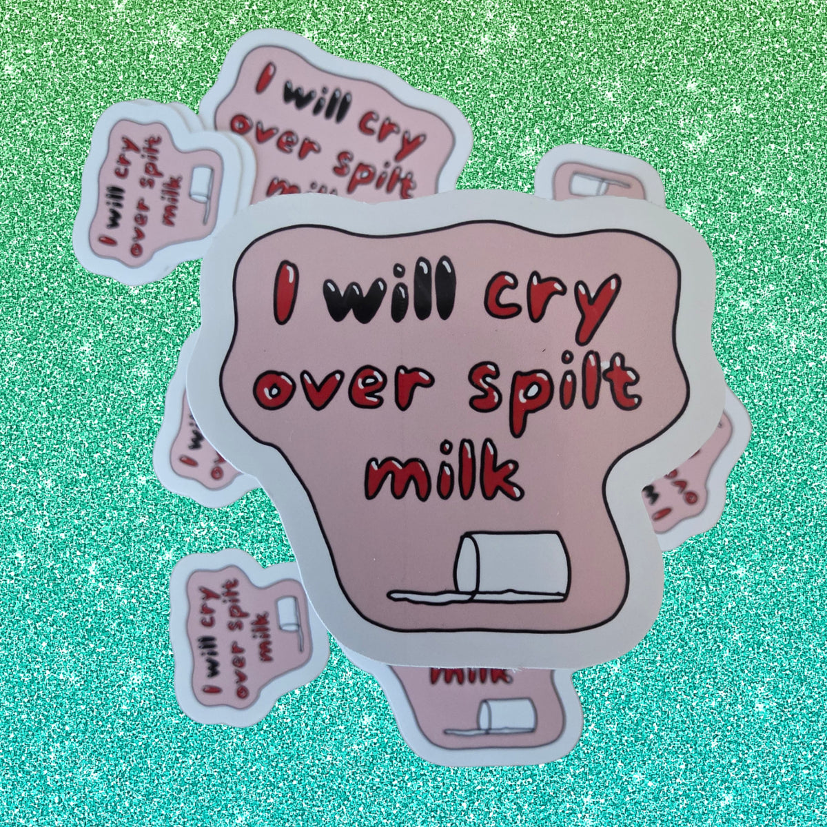 A set of die-cut stickers featuring the text 'I will cry over spilled milk' in red lettering on a pink background, with a small spilled milk carton illustration. The stickers are arranged on a sparkling teal background.