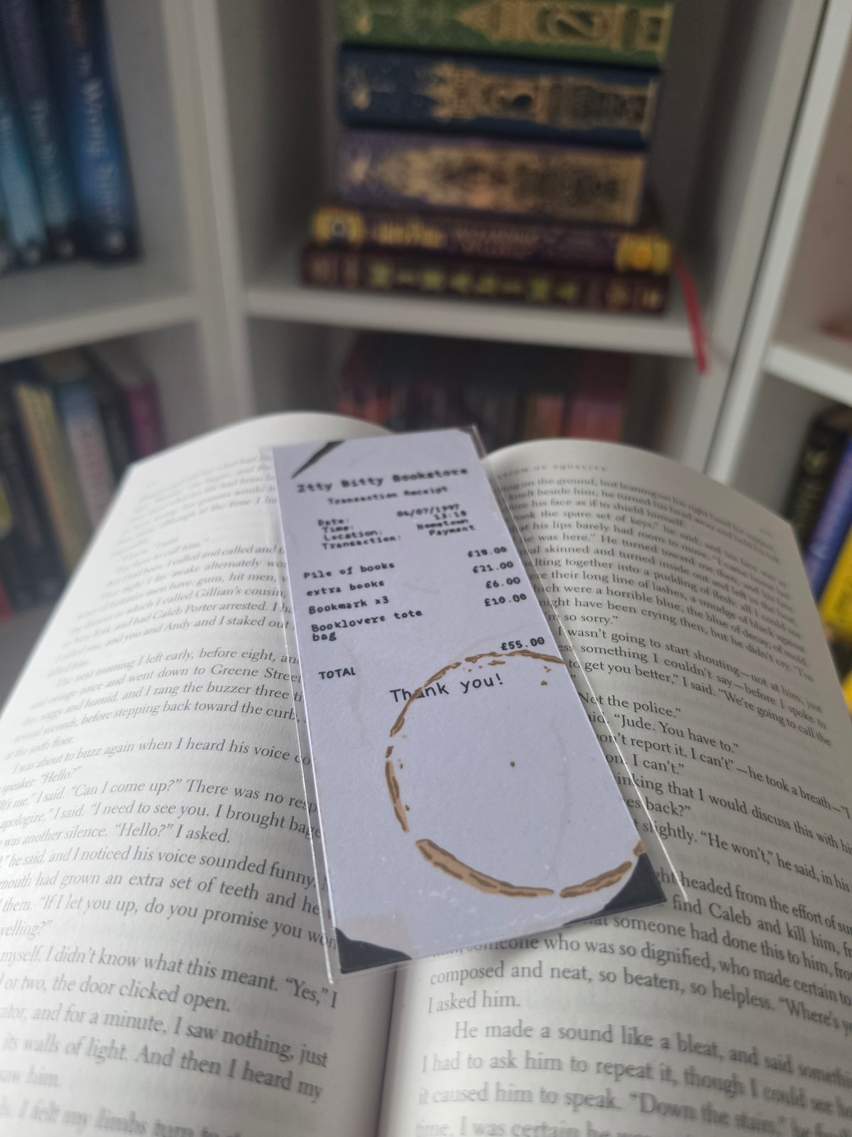 a bookmark made to look like a bookshop receipt with coffee staining and wrinkles, displayed on an open book