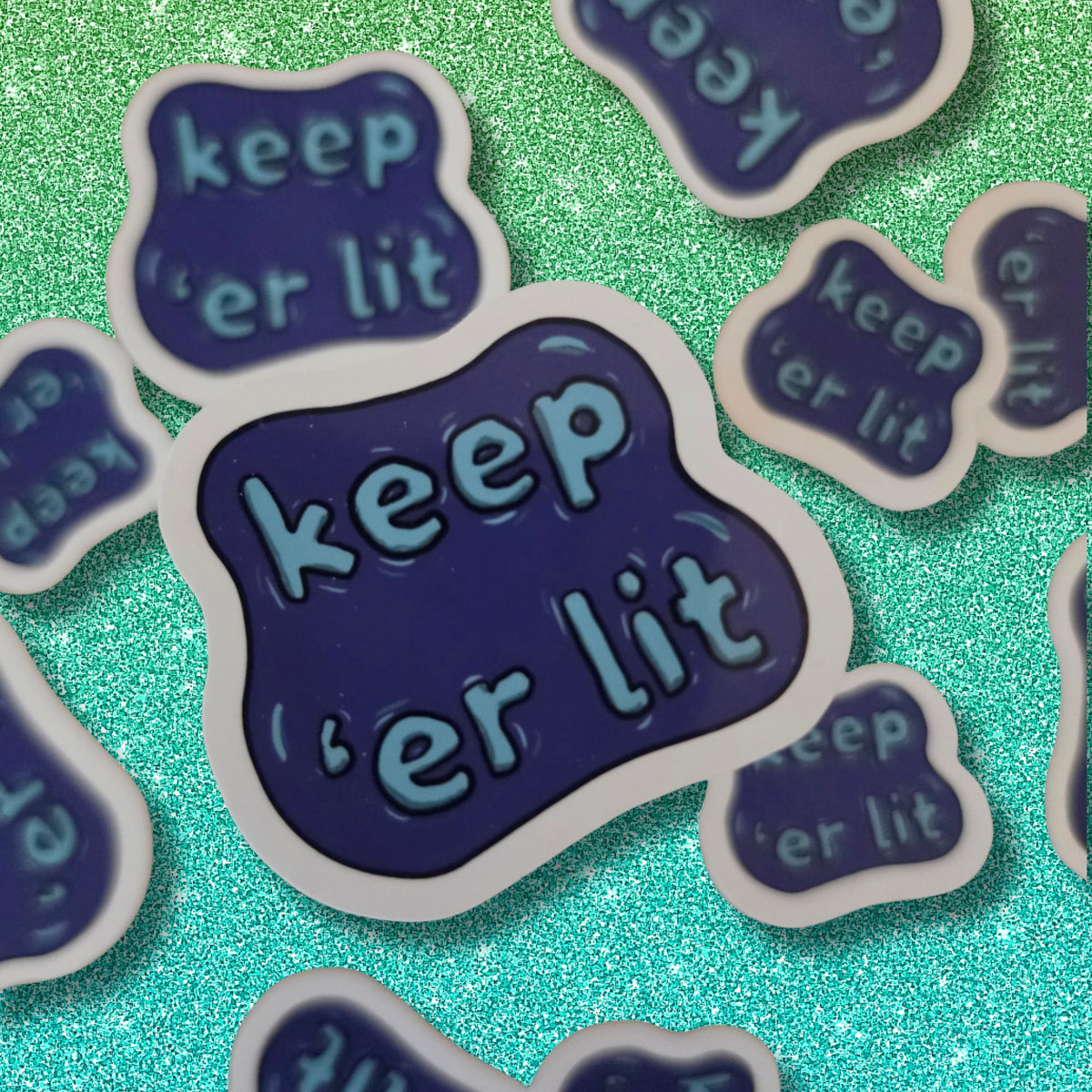 diecut sticker of a norn iron saying "keep er lit"