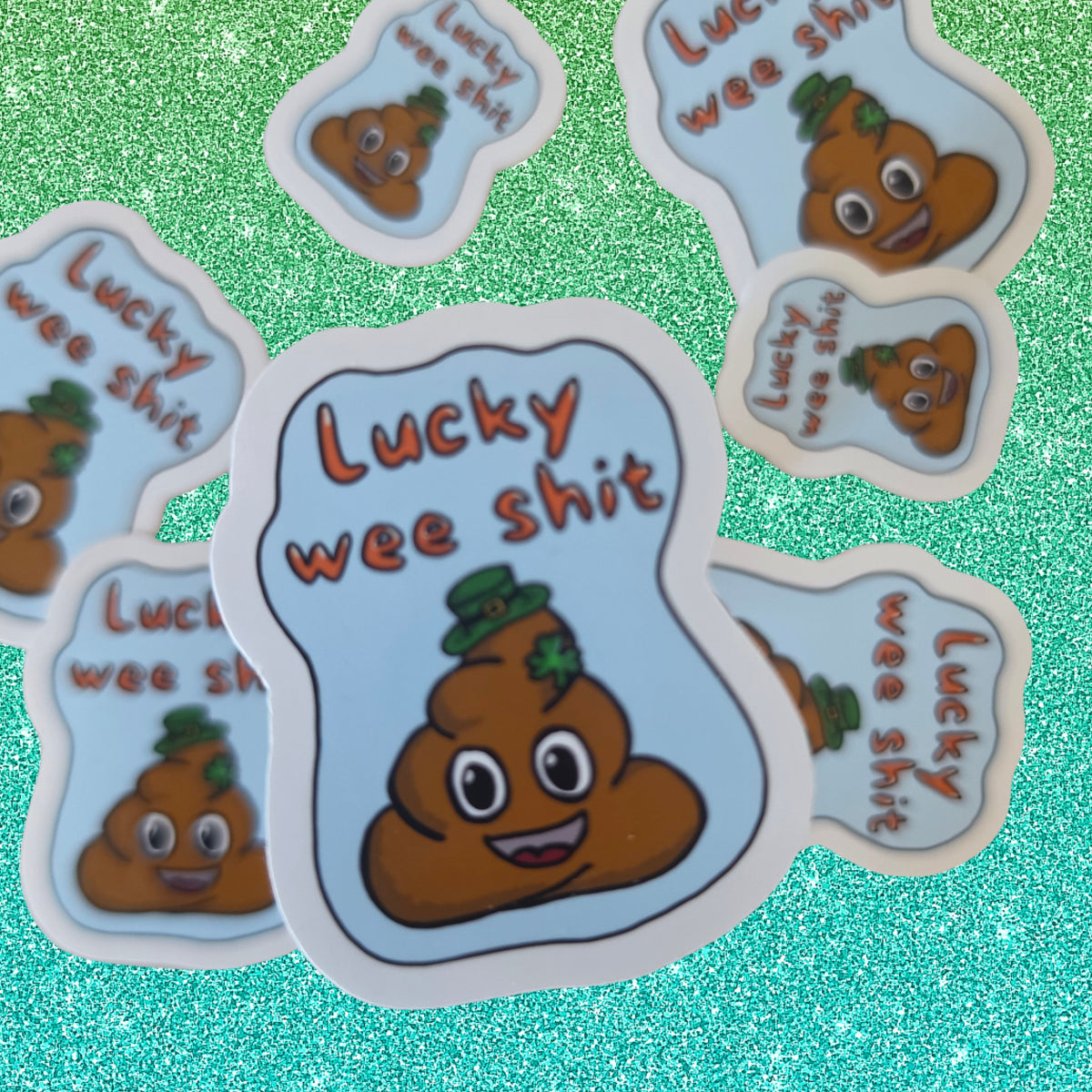 A set of die-cut stickers featuring a cartoon poop emoji wearing a green hat with the text 'Lucky wee shit' on a glittery teal background.