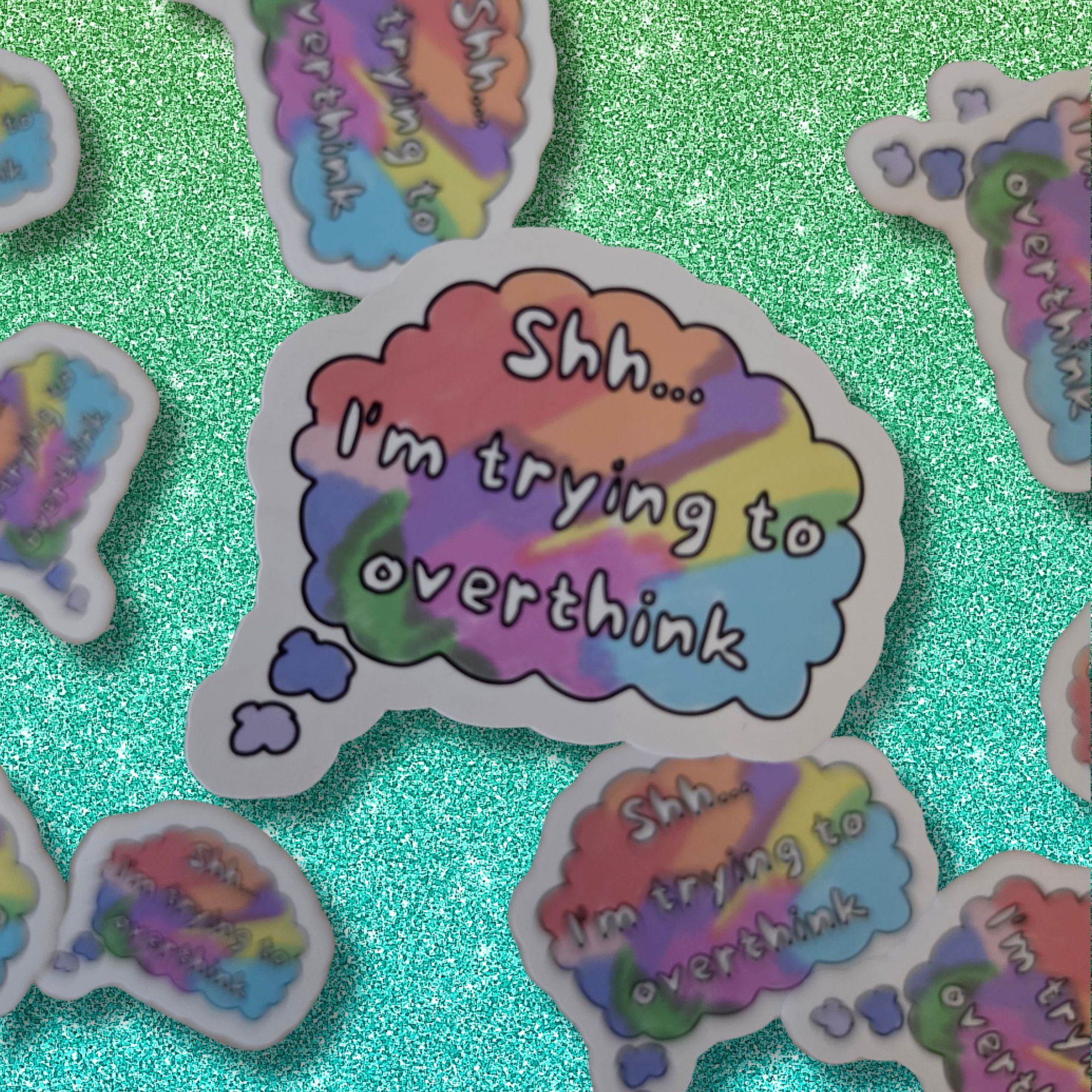 A die-cut sticker featuring a pastel rainbow thought bubble with the text 'Shh.