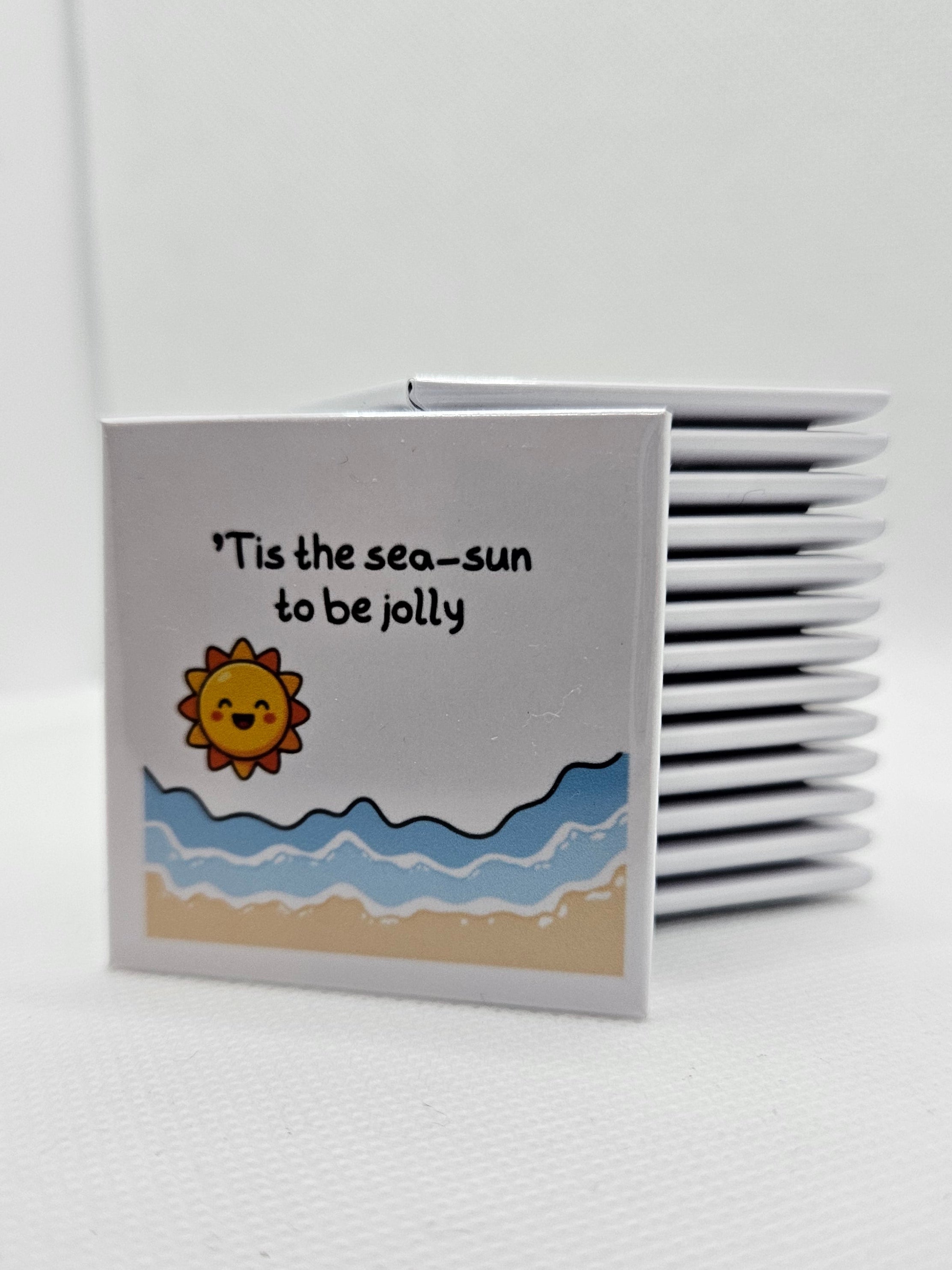 white magnet with a cartoon of the sun, sea and sand words Tis the sea sun to be jolly